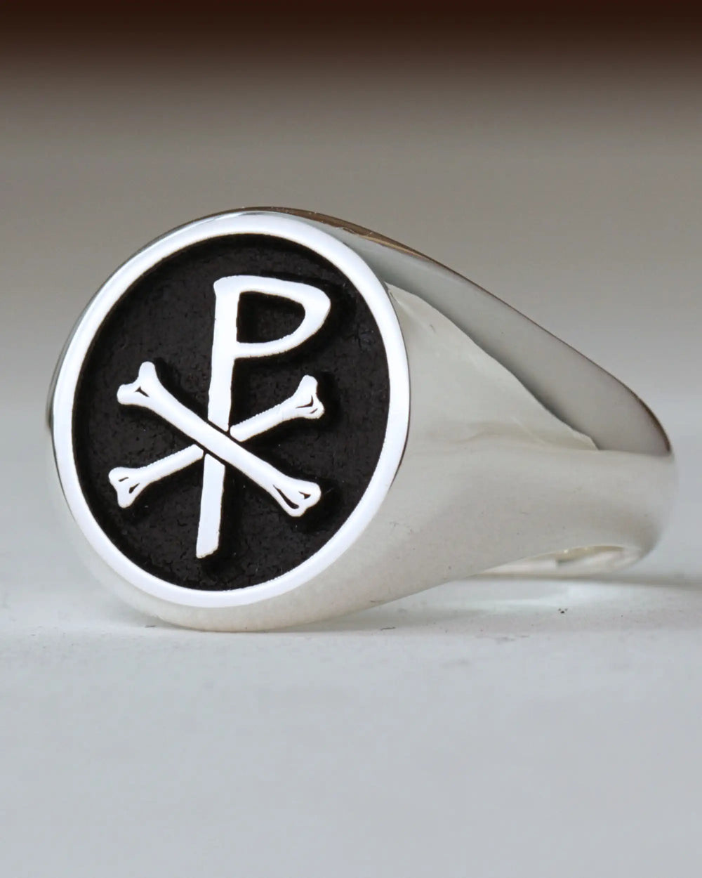 Silver-finish signet ring engraved with the Chi-Rho Christian symbol on a black background